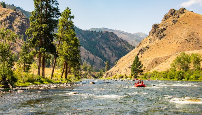 Red raft floating downstream on the Middle Fork Salmon River on a sunny day