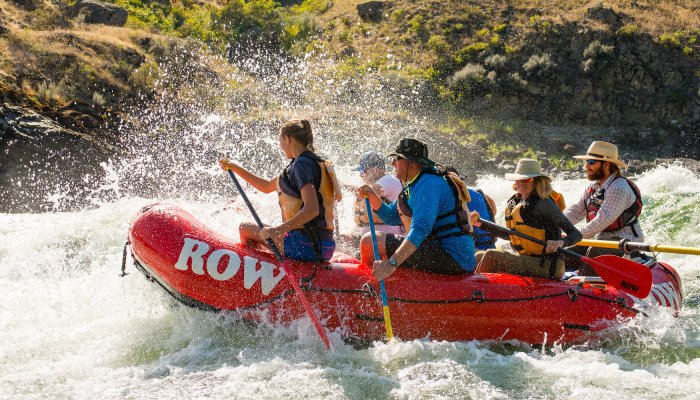 Side view of a red raft paddling through a rapid on the lower Salmon River