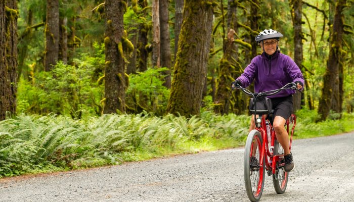 A woman biking through Olympic National park on an e-bike and hike tour with ROW adventures.