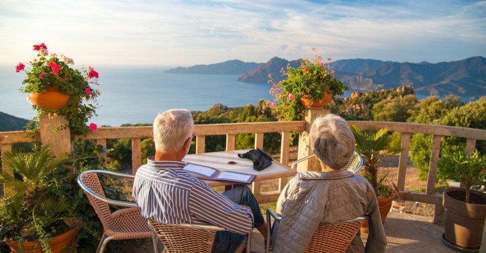 A man and woman sitting at a table overlooking the sea in Corsica